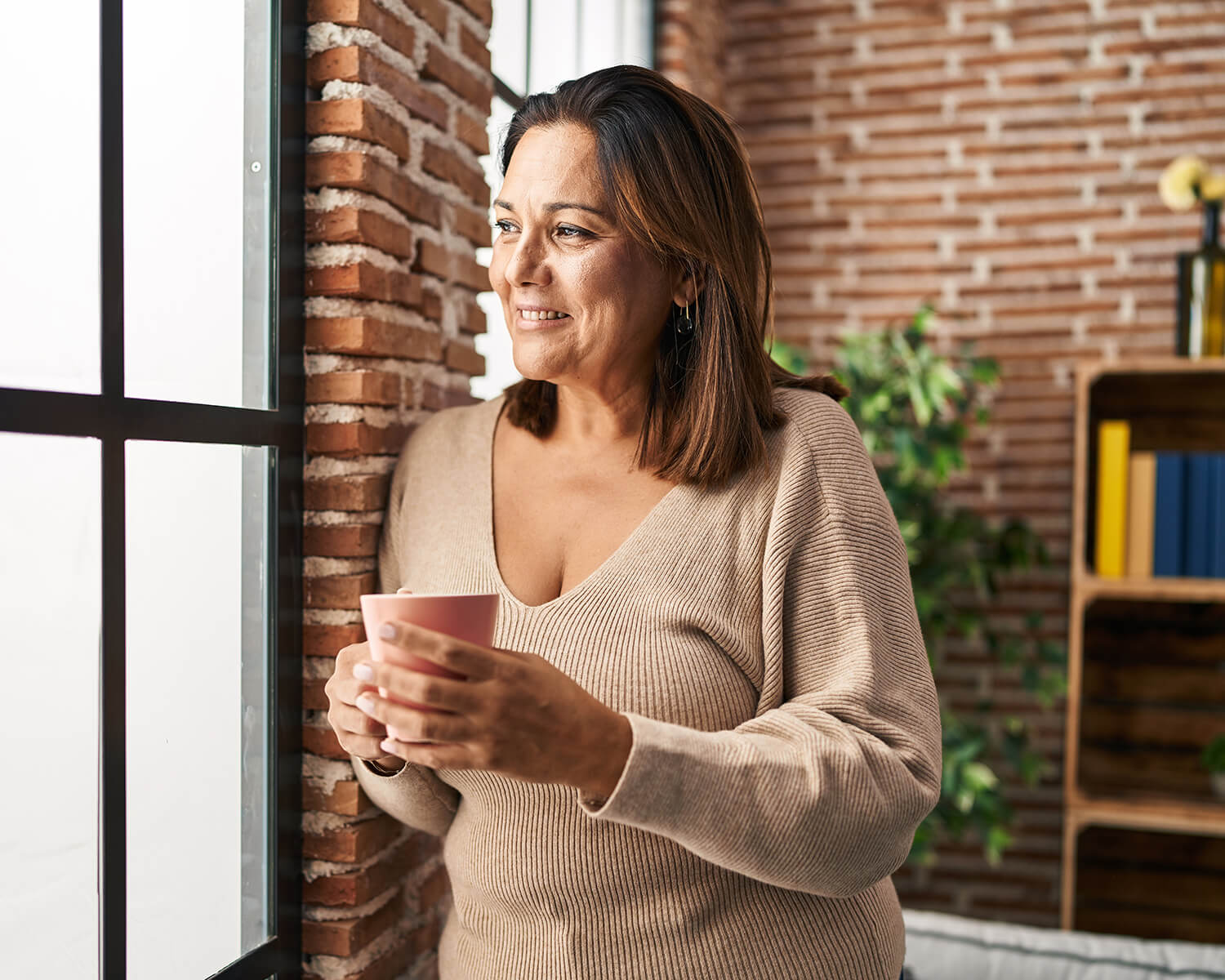 Woman holding a coffee mug by a window