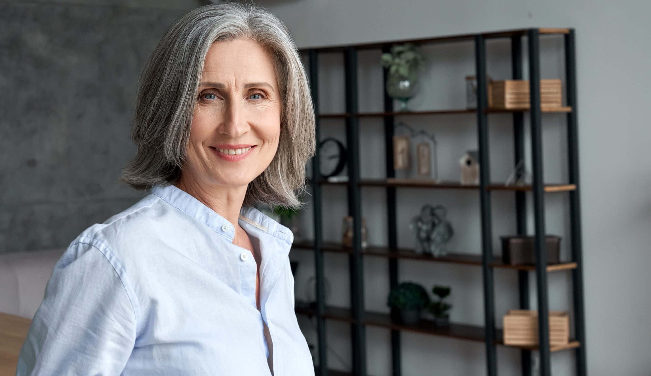 Smiling confident stylish mature middle aged woman standing at home office