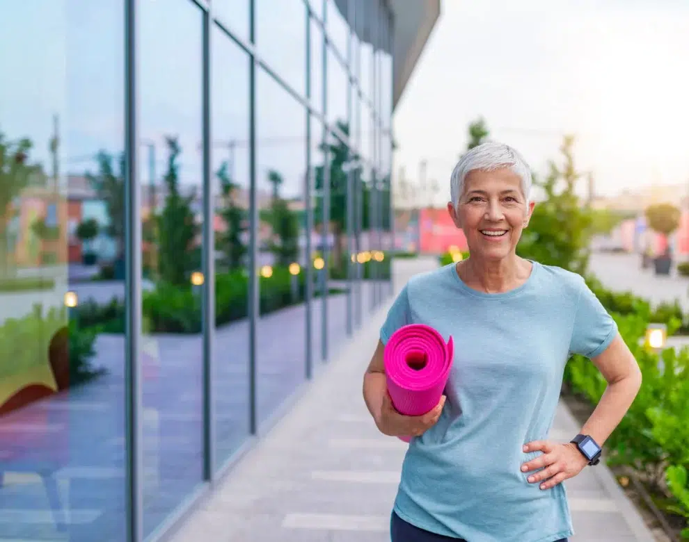 active senior woman with yoga mat