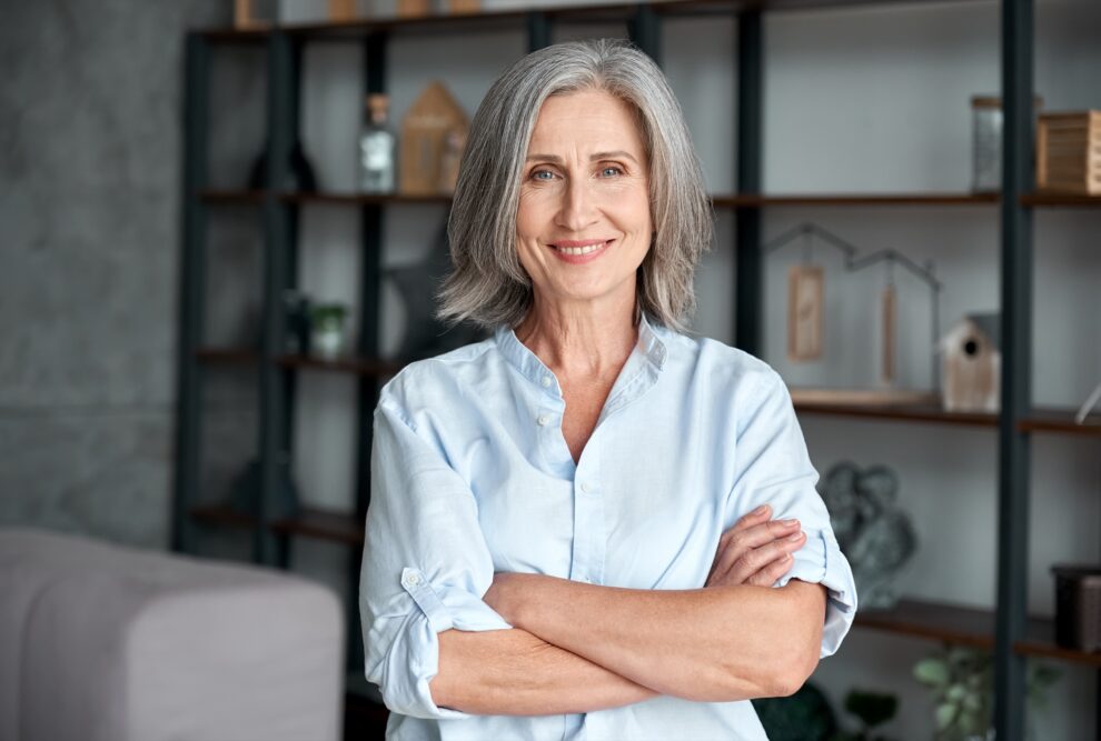 Smiling confident stylish mature middle aged woman standing at home office.